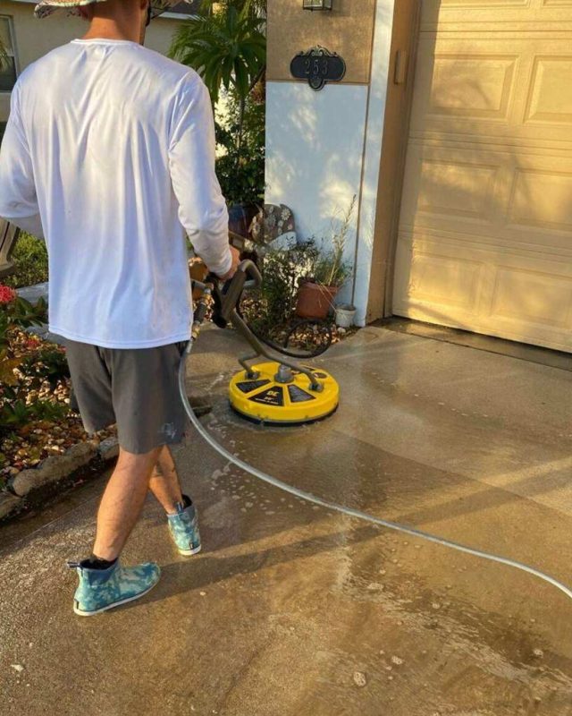 man pressure washing driveway